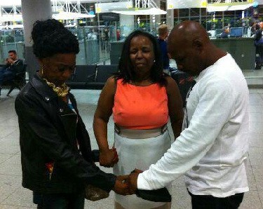 Prominent immigration attorney and Diaspora board member, North East USA, Joan Pinnock (center) offers a word of prayer over Donna (left) and Devon Cameron (right) at JFK International airport, New York on their re-entry as citizens of the United States on Sept. 20, 2015. The pair was deportation 25 years ago. 